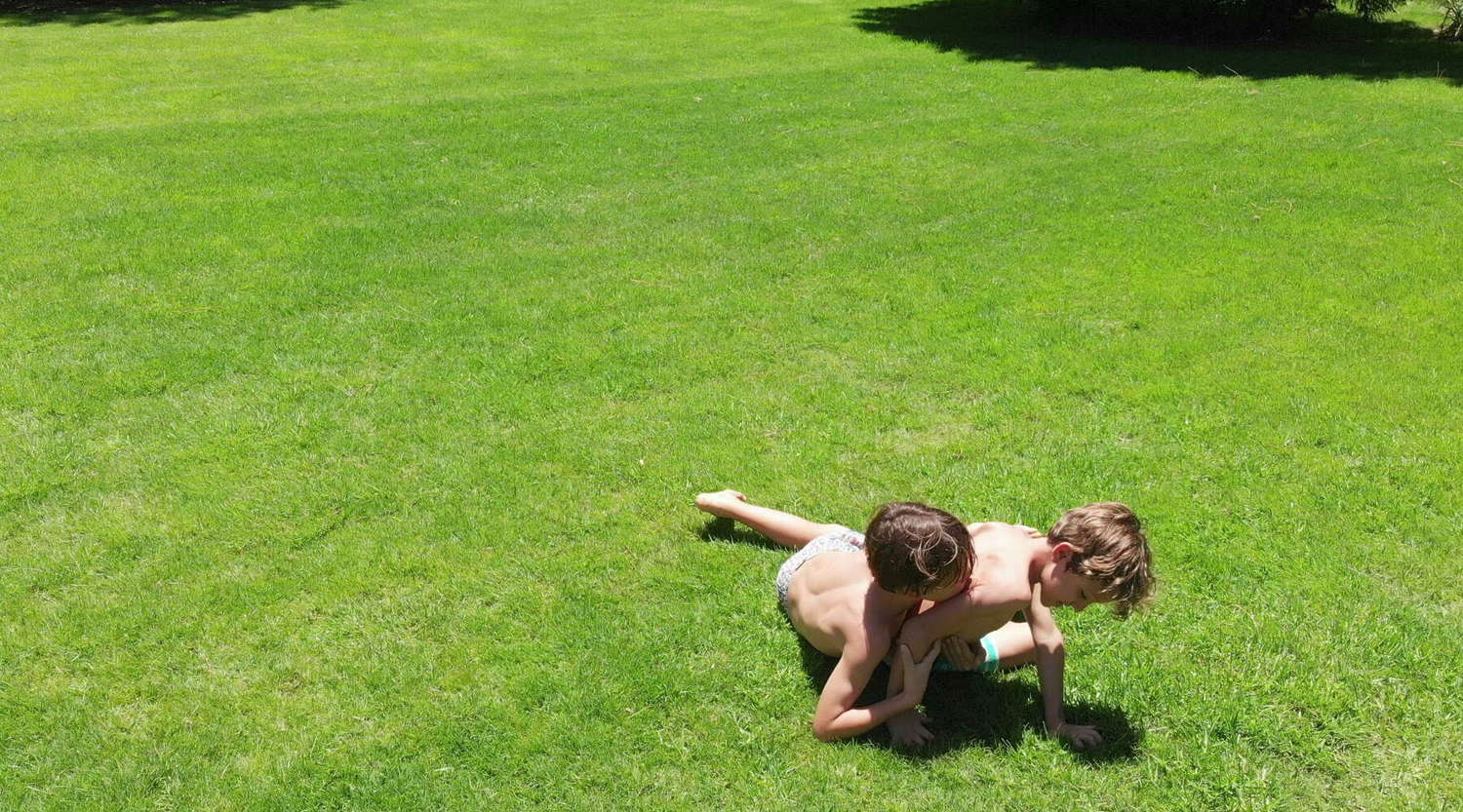 two boys wrestling on the lawn 