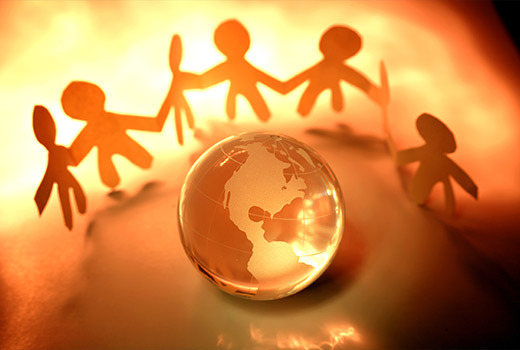 Paper figures holding hands around a globe