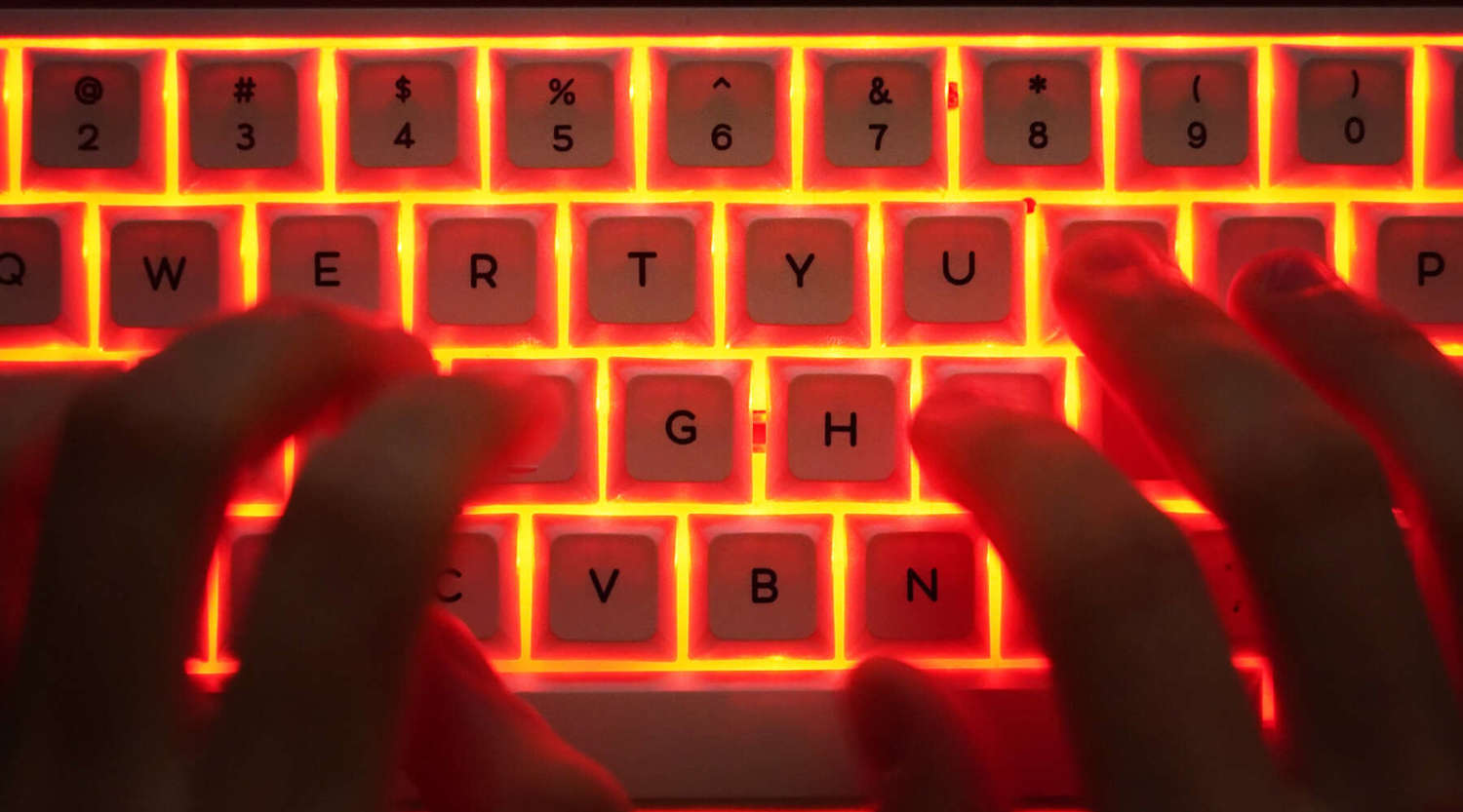 hands typing on illuminated keyboard