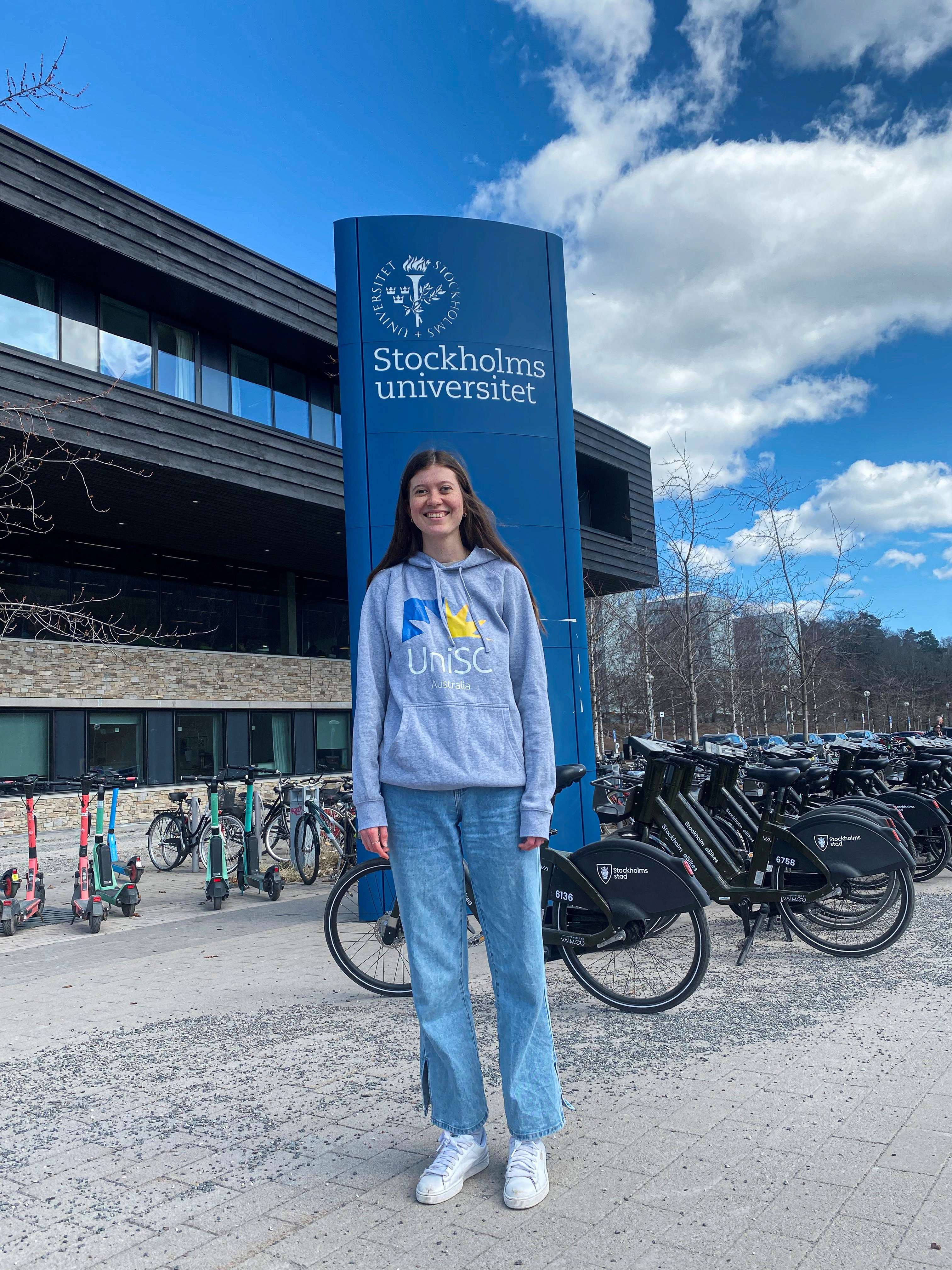 Student standing in front of Stockholm University sign